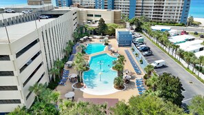 Ein Hotel mit Poolbereich auf dem Dach, mehreren Schwimmbecken und einem Parkplatz.