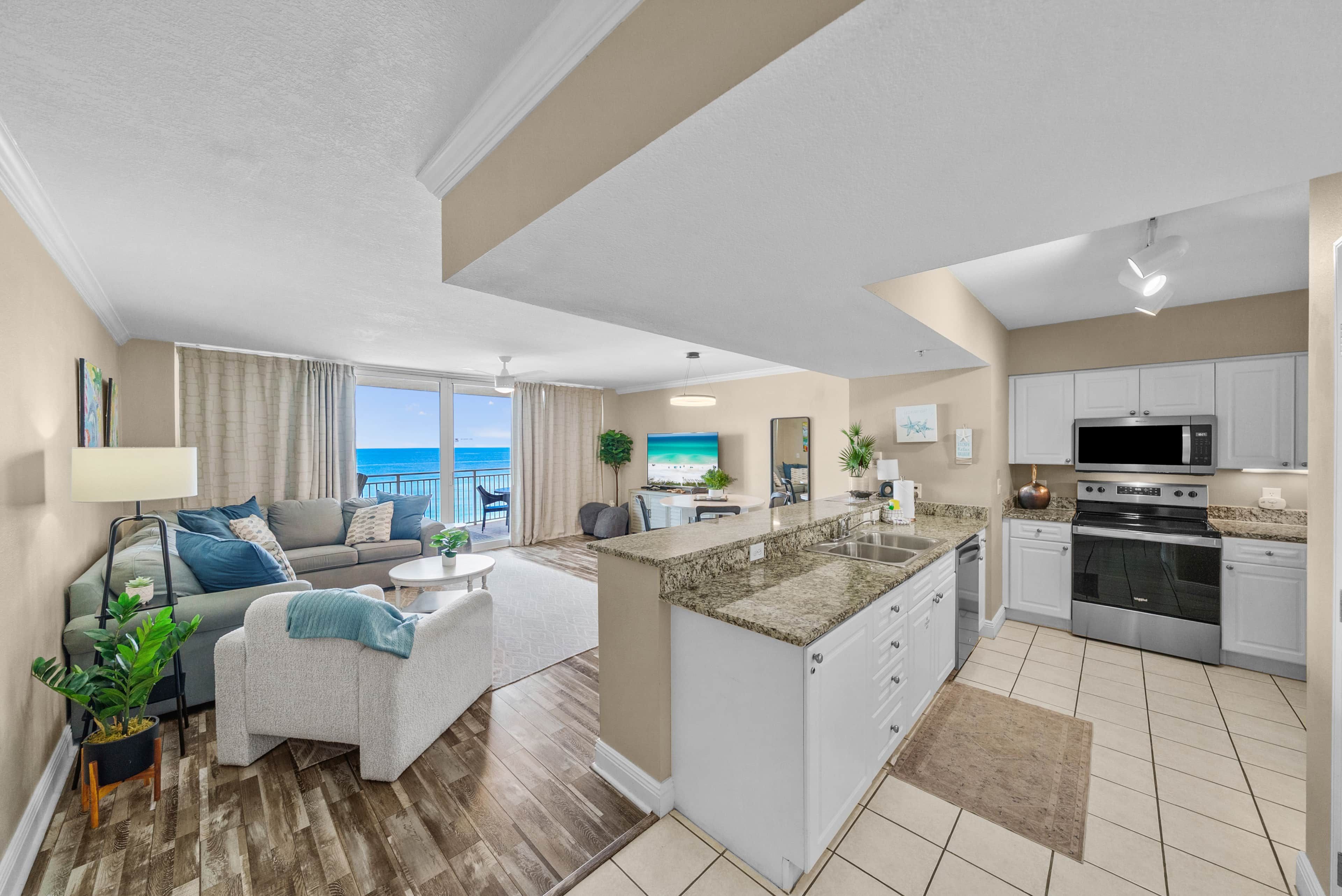 A modern apartment with a living area, kitchen, and a balcony with a view.
