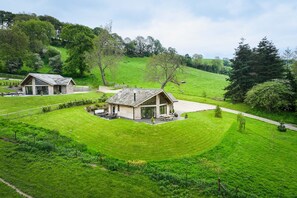 A rural property with two main buildings, a fenced area, and a hilly landscape. - Stylish Holiday Cottage In Rural Montgomery | Llety-Hiraeth (MONTGOMERY)