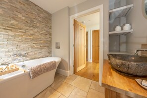 Ein modernes Badezimmer mit einer Steinwand, einer freistehenden Badewanne und einem großzügigen Waschbecken.