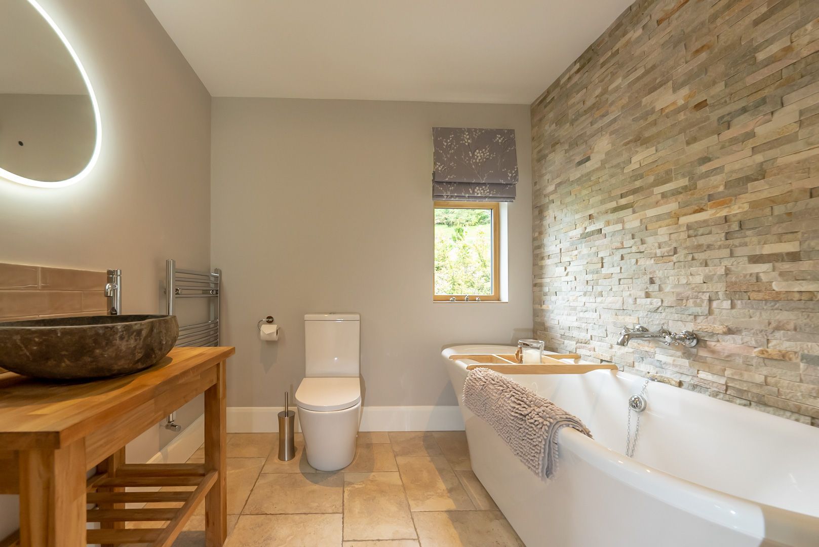 Ein modernes Badezimmer mit einem Steintonne, Toilette und einer Badewanne mit Handtuch.