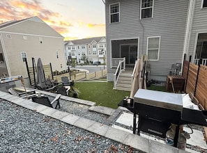 Et boligområde med huse, en terrasse med havemøbler og en lille græsplæne.