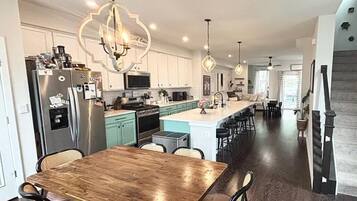A modern kitchen with a central island, stainless steel appliances, and pendant lighting.