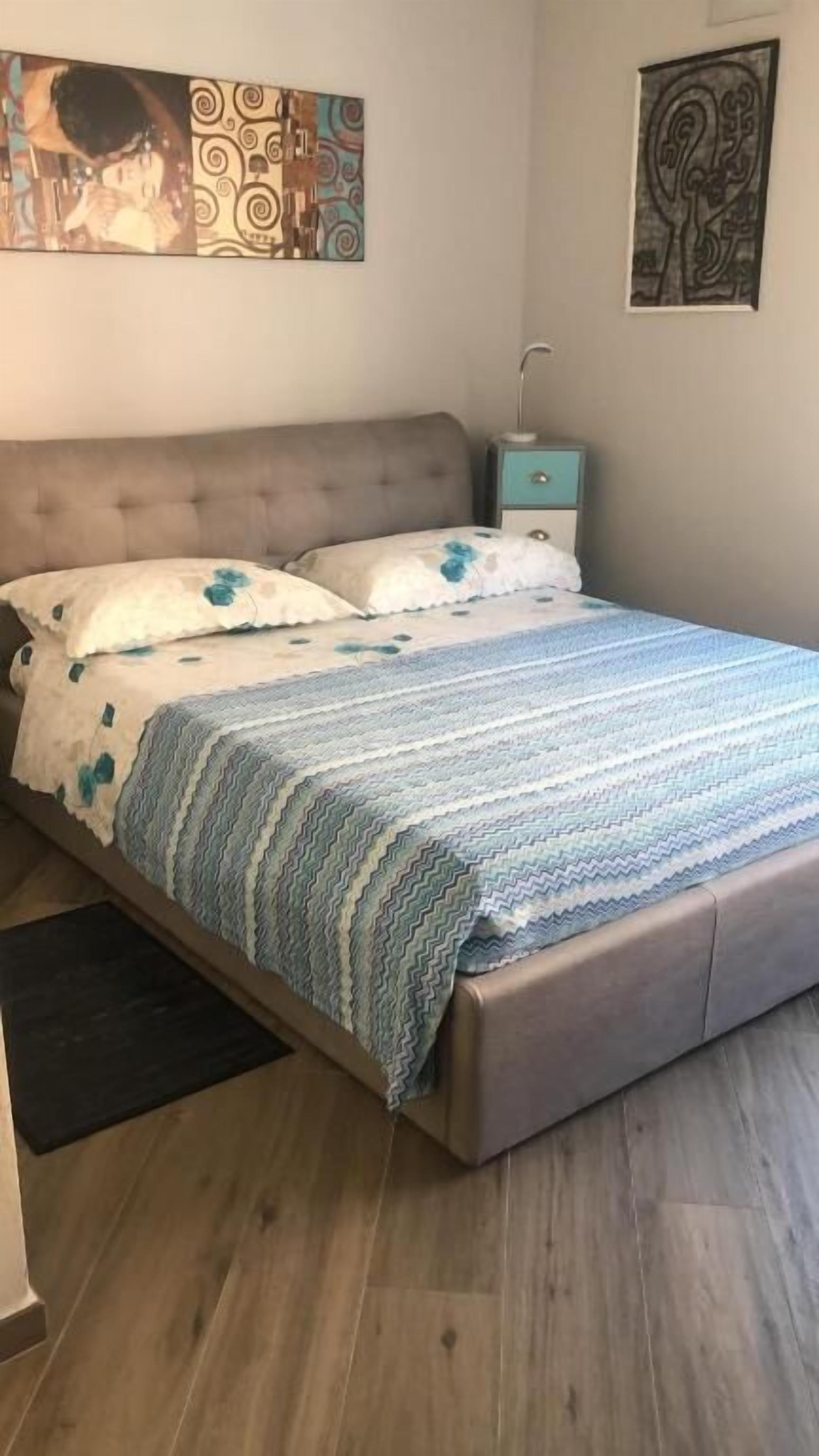 Ein Schlafzimmer mit einem Bett, einem Nachttisch und einem Wandbild.