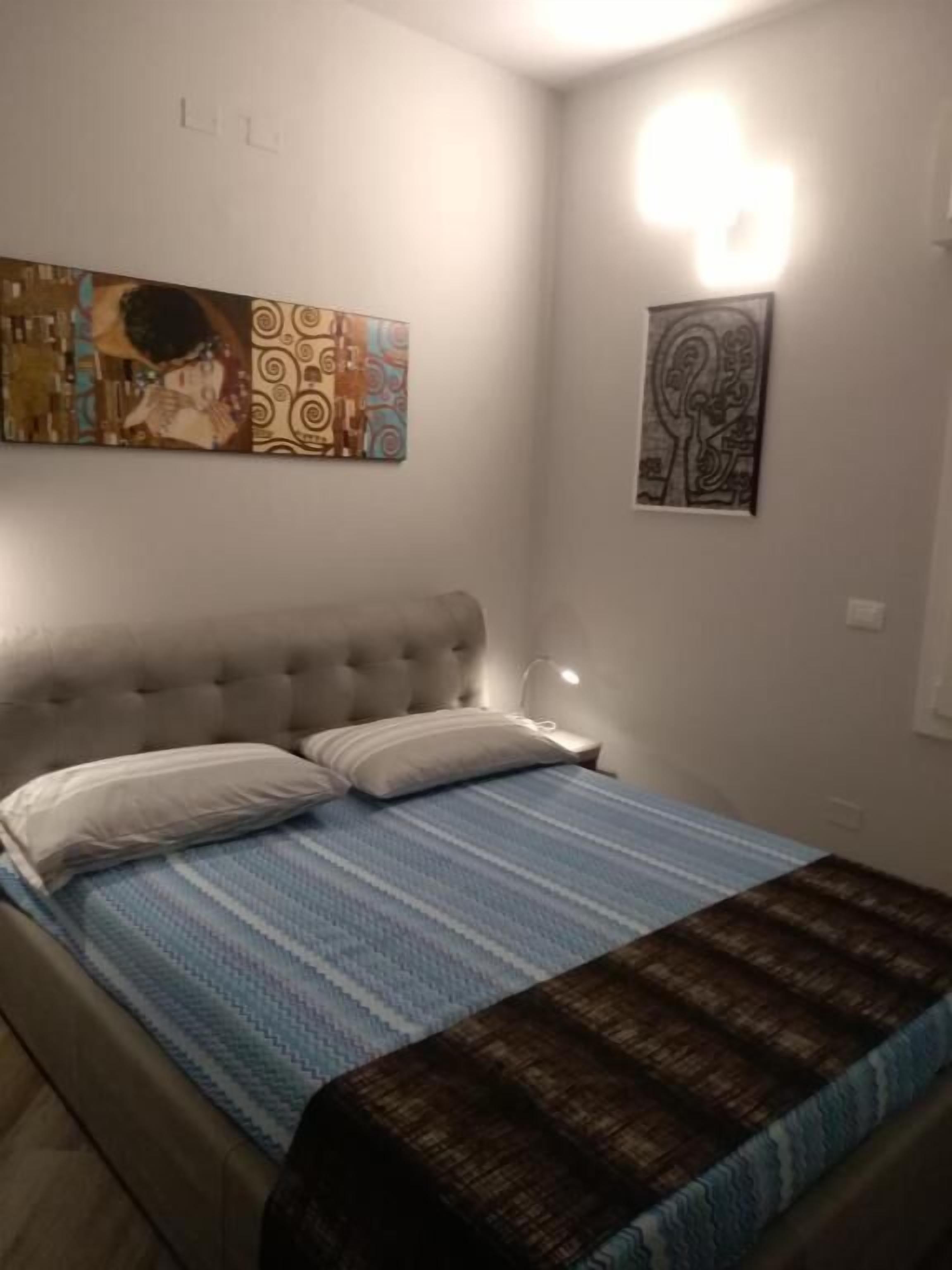 A bedroom with a bed, a headboard, and wall art.