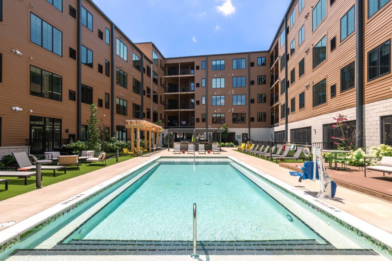 A modern building with a central pool, lounge chairs, and a covered seating area.