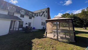 A house with a backyard, a covered patio, and a large window. - The “Dining Room”: A charming 5-bedroom cottage perfect for large families (Port Sydney)