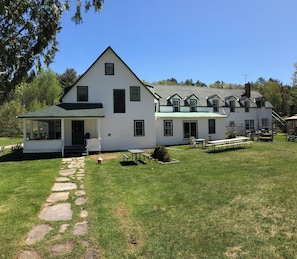 Una casa blanca de dos pisos con un porche cubierto y un sendero de piedra que lleva a la entrada.