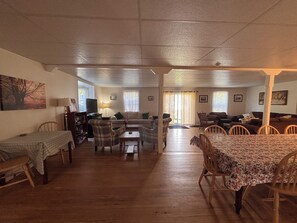 A spacious living area with a sofa, chairs, a dining table, and a television. - The “Dining Room” A 5-bedroom cottage perfect for large families. Clyffe House (Port Sydney)