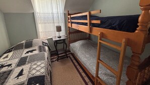 A dormitory room with bunk beds, a desk, a lamp, and a patterned bedspread. - The “Dining Room”: A charming 5-bedroom cottage perfect for large families (Port Sydney)