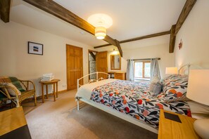 A bedroom with a bed, a chair, a table, and a window. - Three Bedroom Barn Conversion Near Aberporth | Stabal-Y-Rhiw (Penparc)