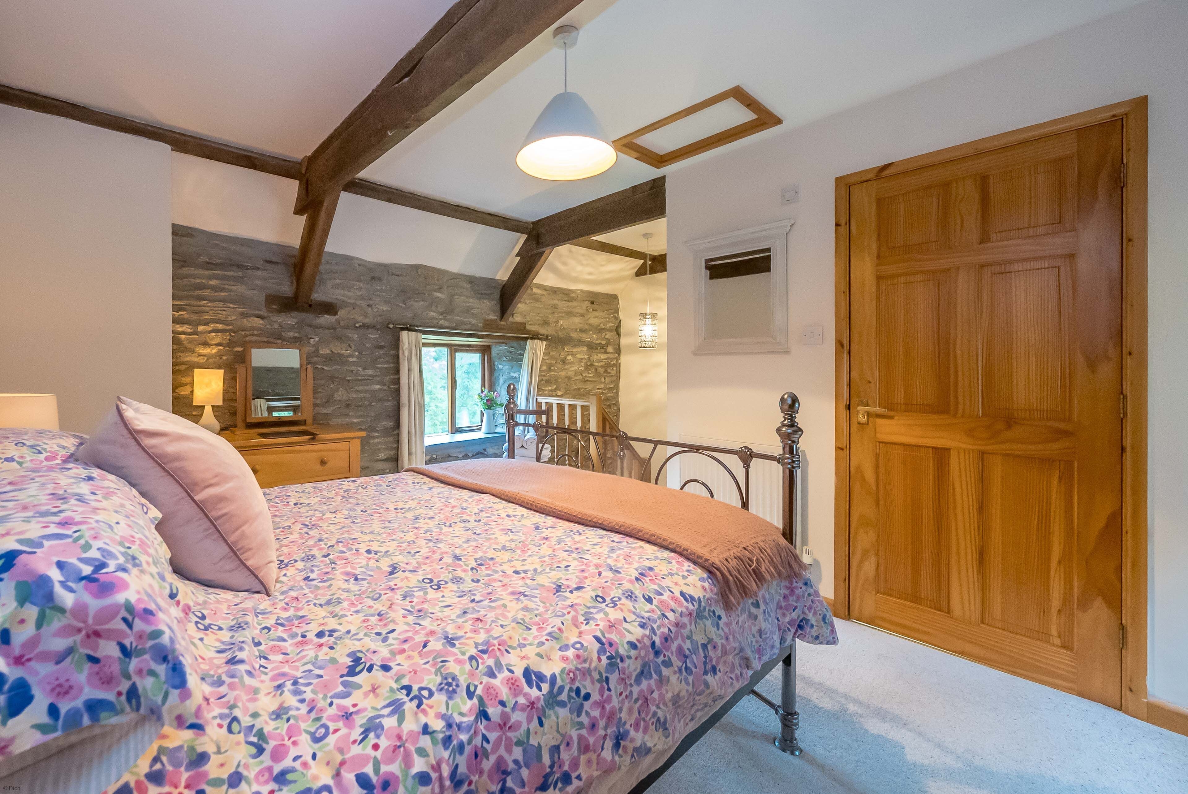 Une chambre à coucher avec un lit, une porte en bois et un mur en pierre.