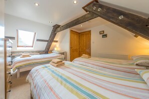 Un dormitorio con dos camas, una viga de techo de madera, un ventanal y un radiador.