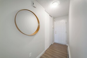 Ein Flur mit Holzboden, einer weißen Tür und einem runden Spiegel an der Wand.