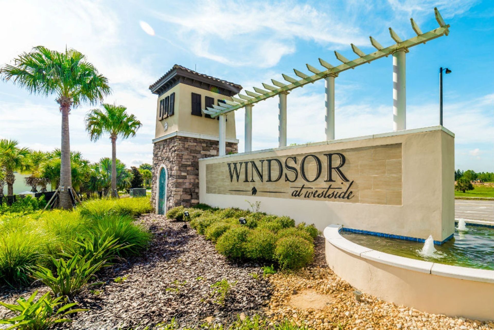 A sign for 'Windsor at Westside' with a pergola structure above it, surrounded by greenery and a water feature.