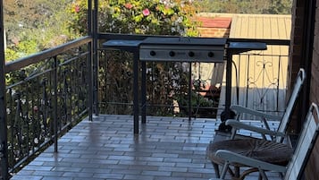 Un balcon avec un sol en briques, une rambarde en métal et une table avec des chaises.