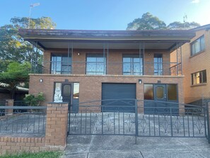 A two-story brick building with a garage door, a metal gate, and a stone lion statue. - The Lion’s Gate - family friendly 3-bedroom house moments from the beach (Catalina)