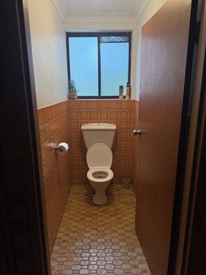 A small bathroom with a toilet, a window, and patterned tiles. - The Lion’s Gate - family friendly 3-bedroom house moments from the beach (Catalina)