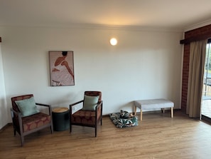 A living room with two armchairs, a bench, a small table, and a wall-mounted picture.