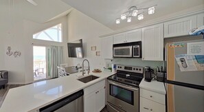 A modern kitchen with white cabinetry, a built-in microwave, a stove, and a refrigerator. - Gulf Shores Escape with Breathtaking Views, Beach Days & Unforgettable memories (Gulf Shores)