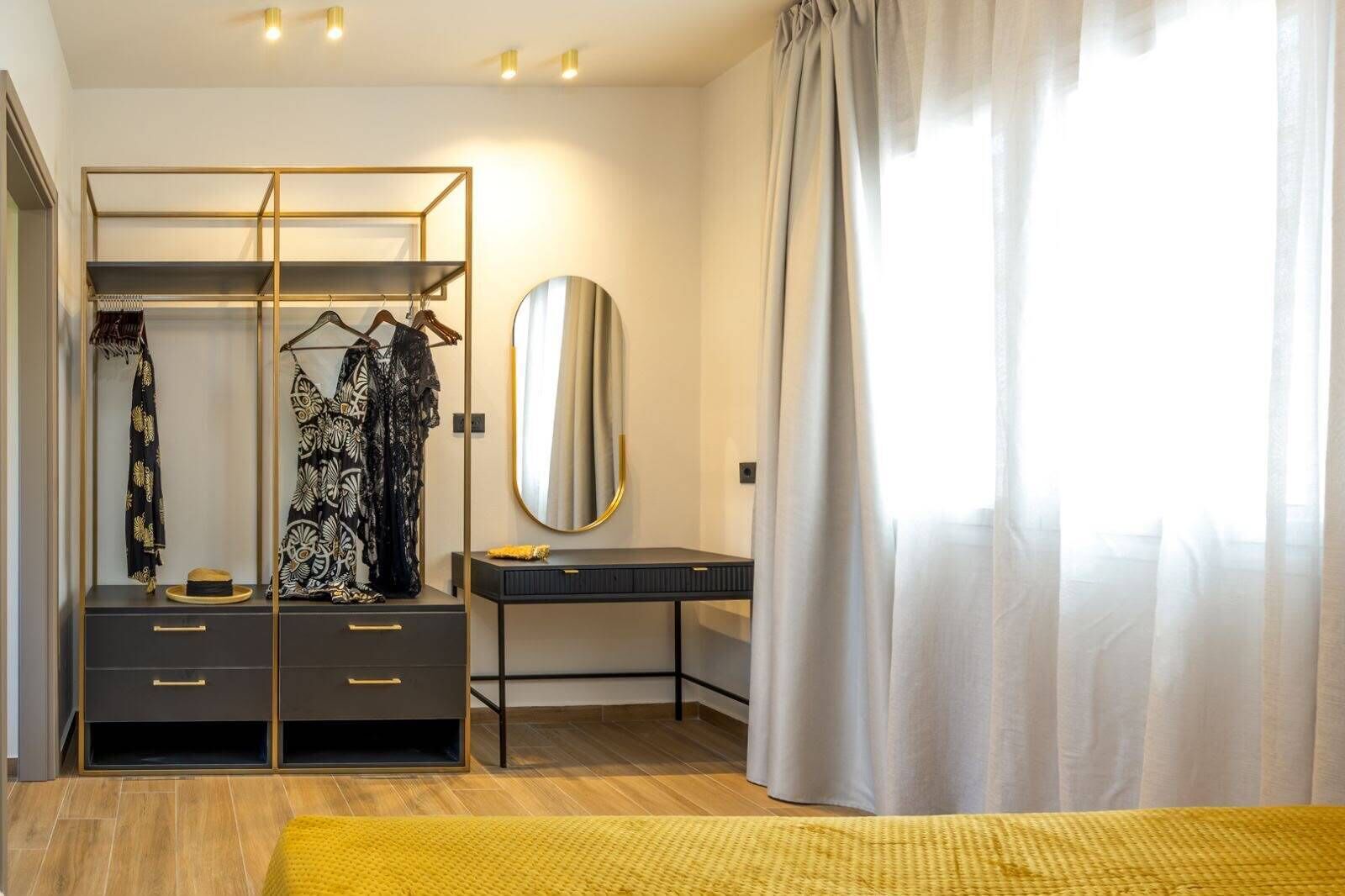 Ein Schlafzimmer mit Kleiderschrank, Schminktisch mit Spiegel und einem Bett mit gelbem Teppich.