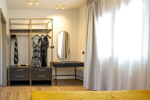 Un dormitorio con un armario, un tocador con espejo y una cama con alfombra amarilla.