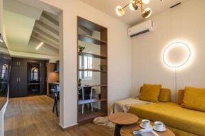 Uma sala de estar moderna com sofá, mesa de centro e área de trabalho com cadeira. Há uma escada que leva a outro andar.