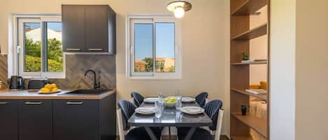 A modern kitchen with dark cabinetry, a herringbone backsplash, and a dining area with a marble table and black chairs.