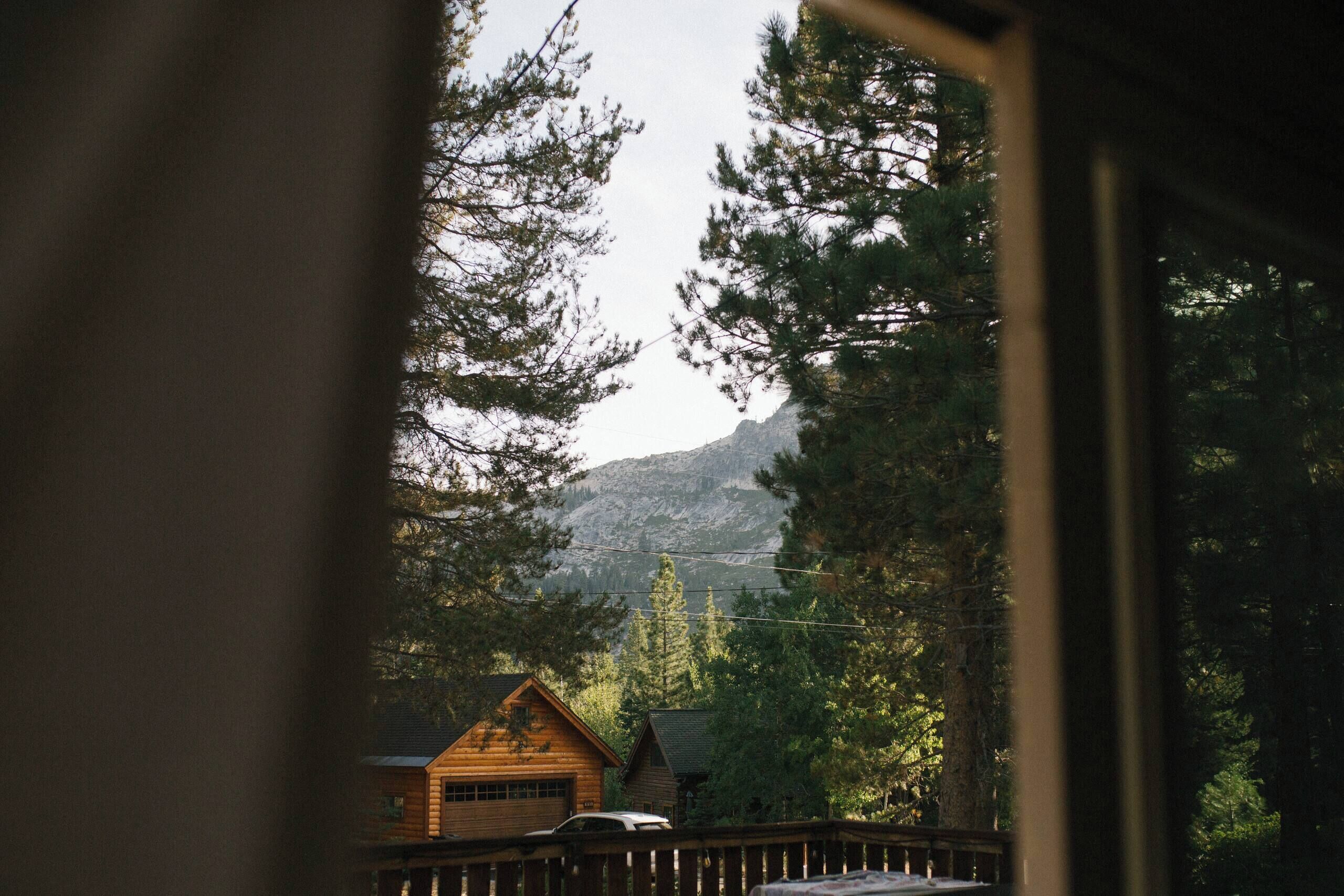 A cabin with a garage, surrounded by dense forest and mountains in the background.