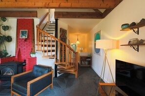 A cozy living room with a fireplace, a wooden staircase, and a television. - The Victorian Garden Retreat (Victoria)