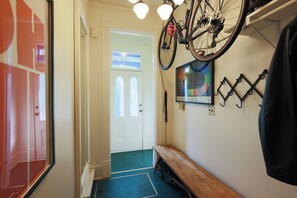 A hallway with a bicycle mounted on the wall, a bench, and a door with a window. - The Victorian Garden Retreat (Victoria)