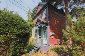A red wooden house with a blue porch and a small staircase leading up to the entrance. - The Victorian Garden Retreat (Victoria)