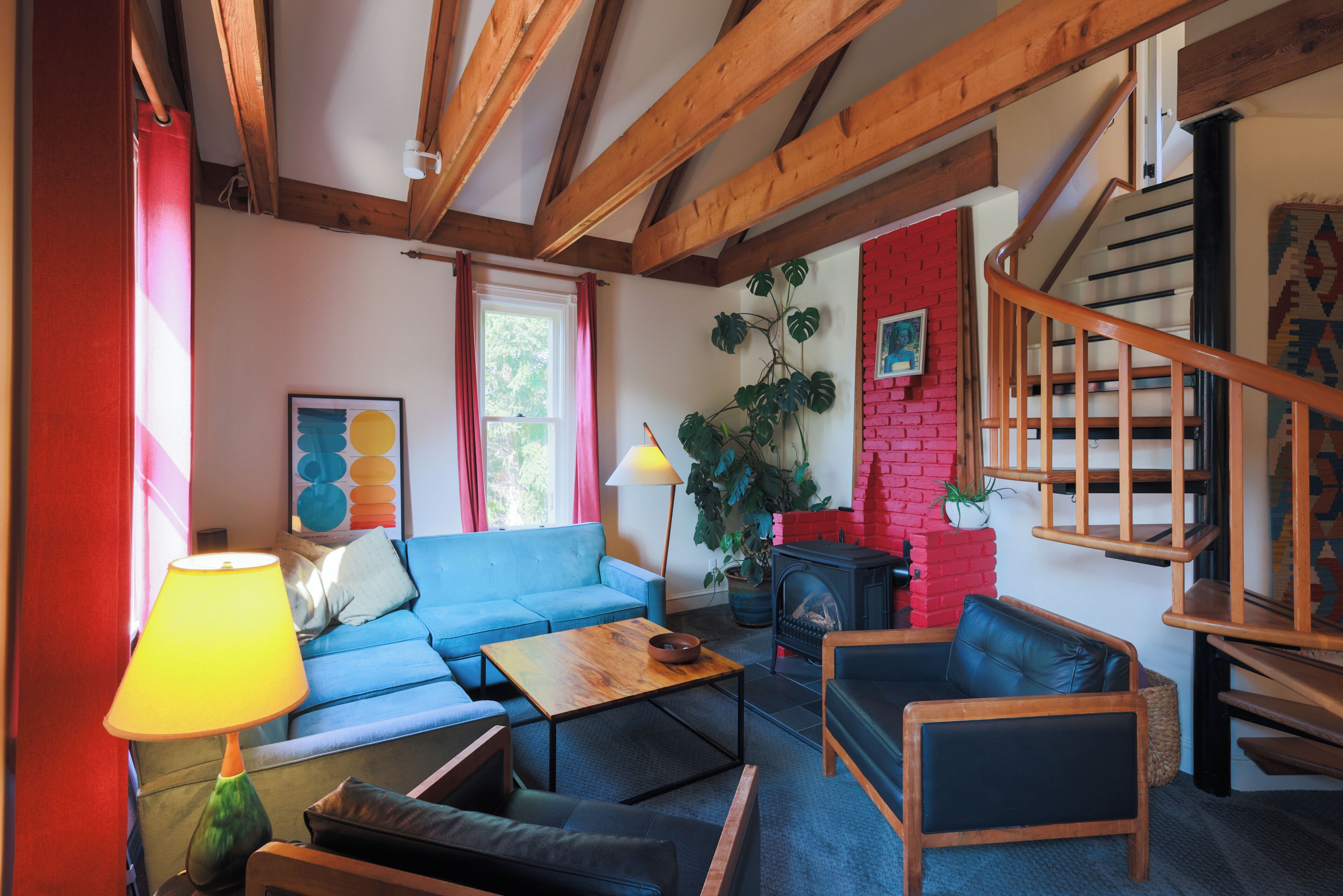 Een woonkamer met een blauwe bank, een houten salontafel, een open haard en een trap.