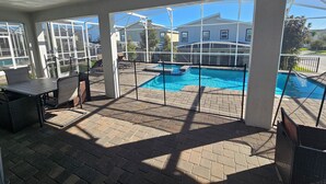 Una veranda coperta con piscina, mobili da esterno e vista sulle case vicine.
