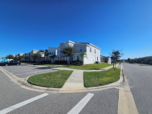 A residential street with modern houses, a clear sky, and a parking lot. - 9BR ChampionsGate Villa | Private Pool & Spa | Game Room | Near Disney (Davenport)