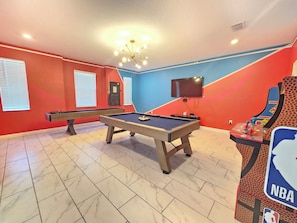 A room with two pool tables, a television, and an arcade machine. - 9BR ChampionsGate Villa | Private Pool & Spa | Game Room | Near Disney (Davenport)