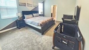Una camera da letto con un letto, comodini, una cassettiera, una televisione e una valigia.