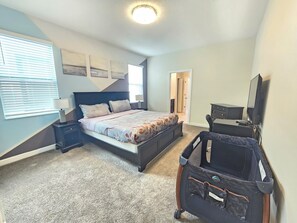 A bedroom with a bed, bedside tables, a dresser, a television, and a suitcase. - Marvelous 9-bedroom house with AC in peaceful Davenport (Davenport)