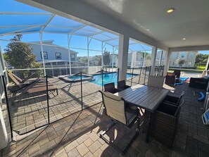 A covered outdoor area with a pool, seating, and a view of surrounding buildings. - Marvelous 9-bedroom house with AC in peaceful Davenport (Davenport)