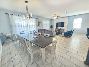 Un coin repas avec une table et des chaises, un canapé, un téléviseur et un ventilateur de plafond.