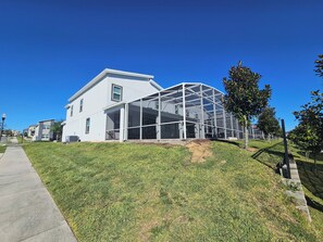 A modern house with a large glass extension, a grassy yard, and a sidewalk. - Marvelous 9-bedroom house with AC in peaceful Davenport (Davenport)