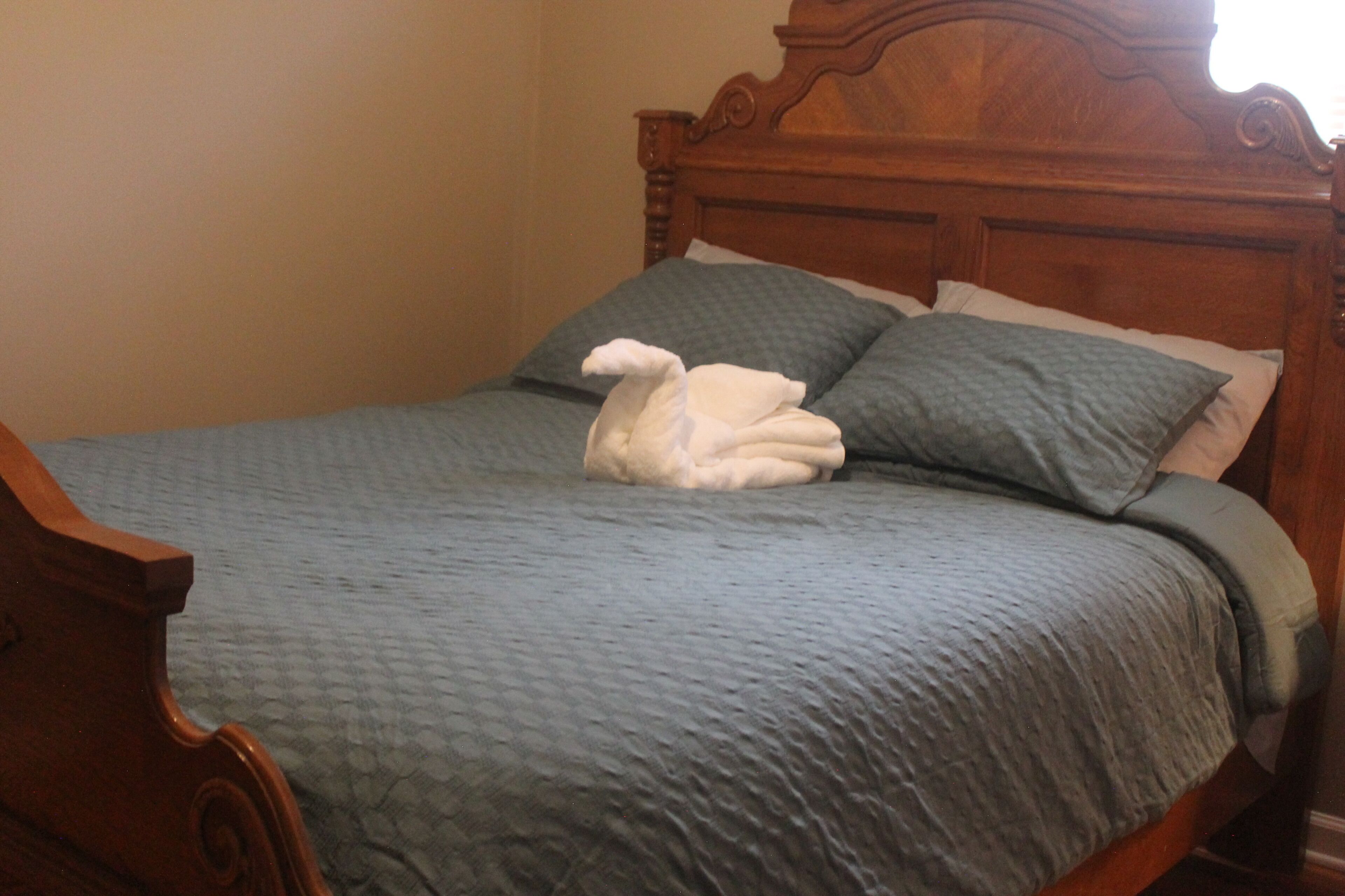A bed with a blue bedspread and pillows, a wooden headboard, and a wooden nightstand.