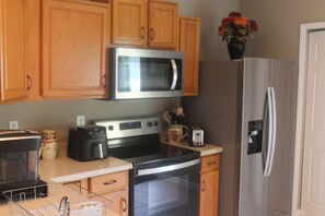 A kitchen with wooden cabinets, a microwave, a toaster, and a refrigerator. - Cozy Mountain Home (East Flat Rock)