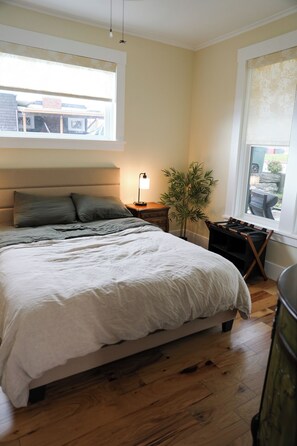 A bedroom with a large bed, bedside lamp, and a potted plant.