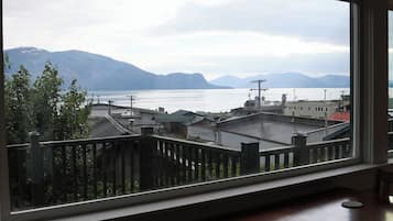 A room with a large window overlooking a cityscape, a wooden table, and a chair.