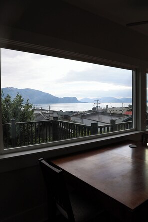 A room with a large window overlooking a cityscape, a wooden table, and a chair.