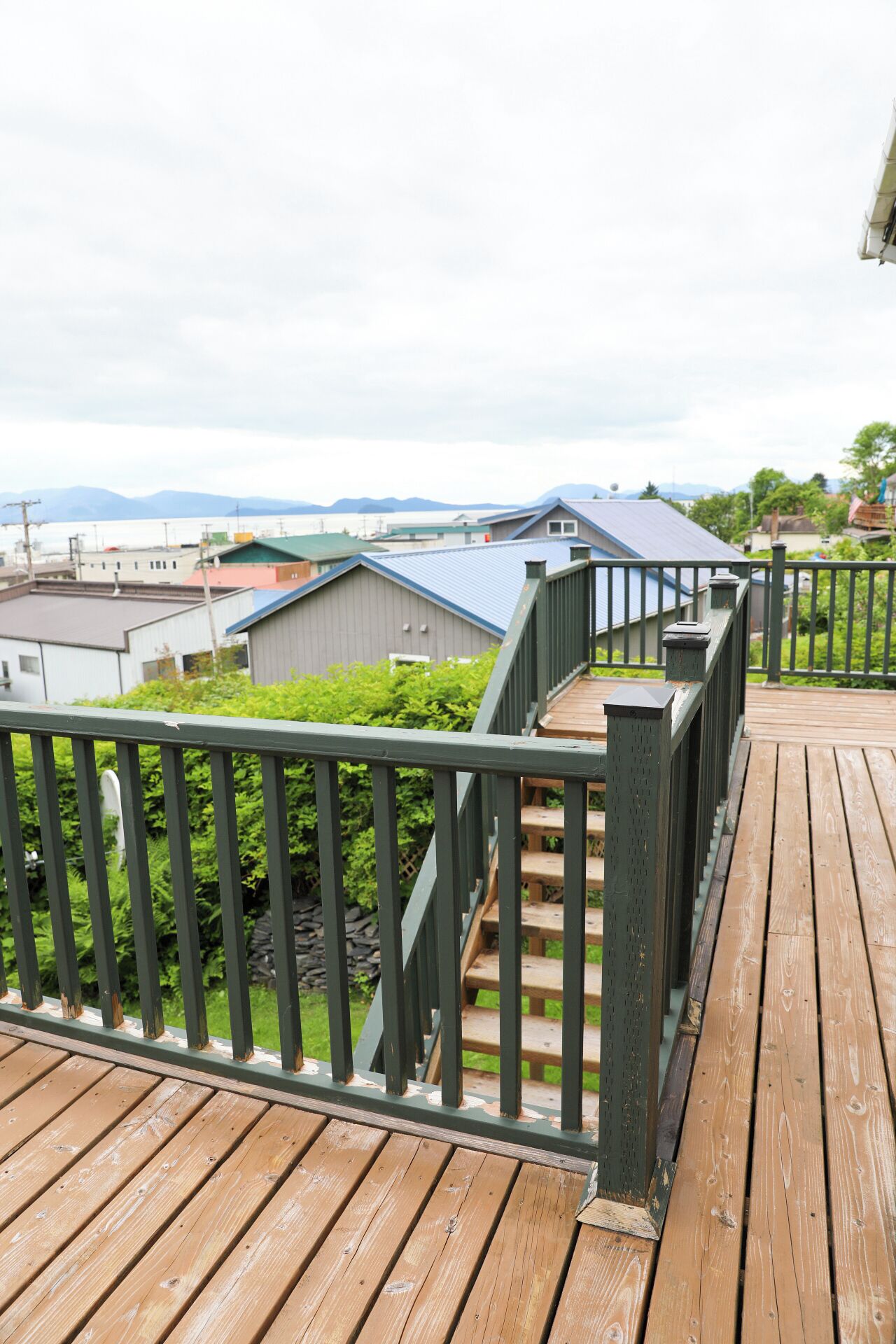 A wooden deck with a metal railing, leading to a staircase.