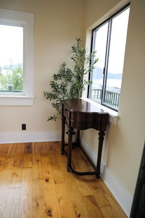 A room with a wooden floor, a dark wooden table, a potted plant, and a window with a view of the outdoors. - The Byrd House — Charming 3-bedroom, 3-livingroom Oceanview house in Wrangell (Wrangell)