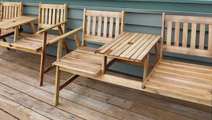 Eine Holzterrasse mit einer Sitzgruppe aus einem Tisch und vier Stühlen.