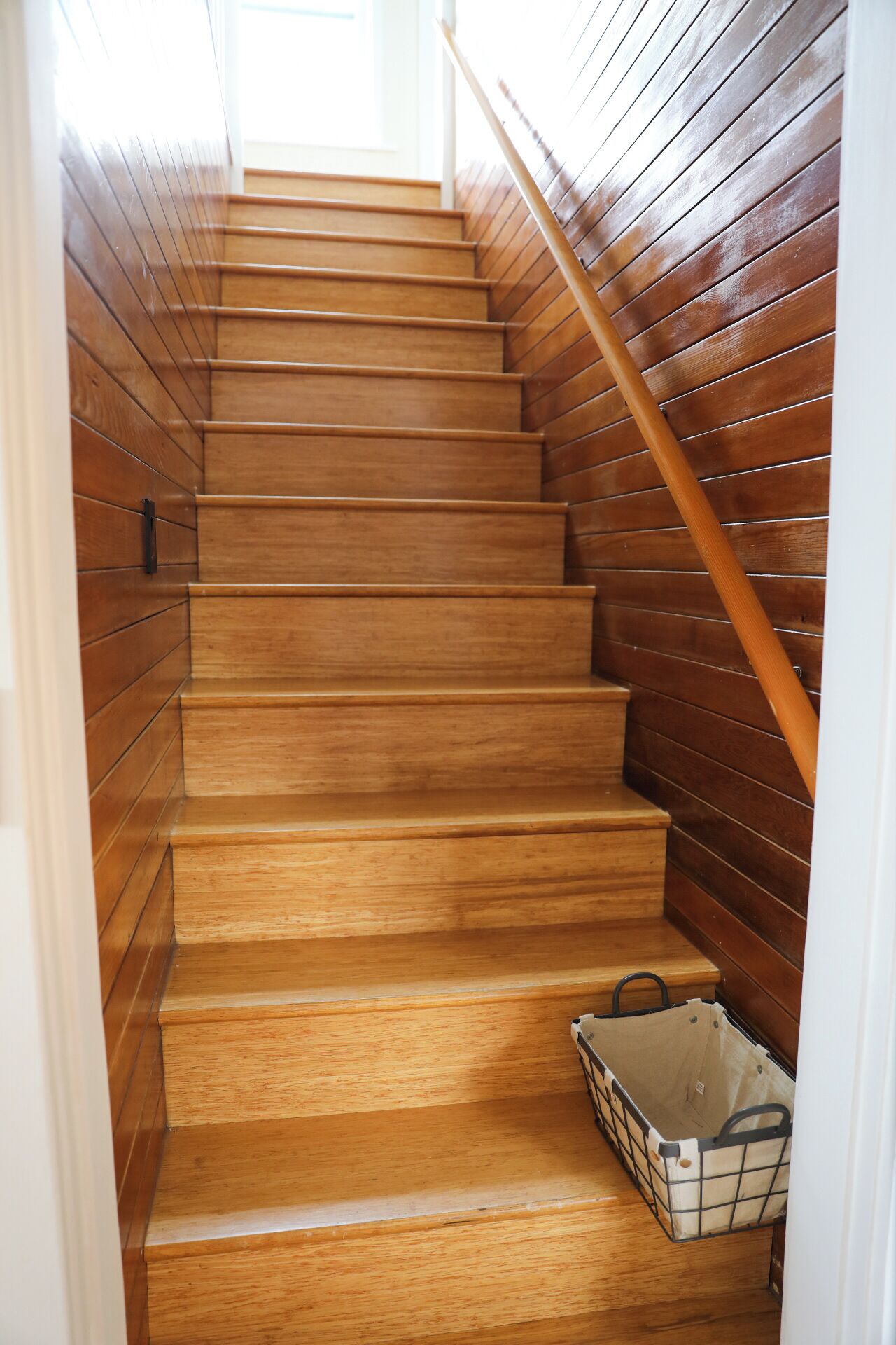 A wooden staircase with a handrail, leading to an upper floor.